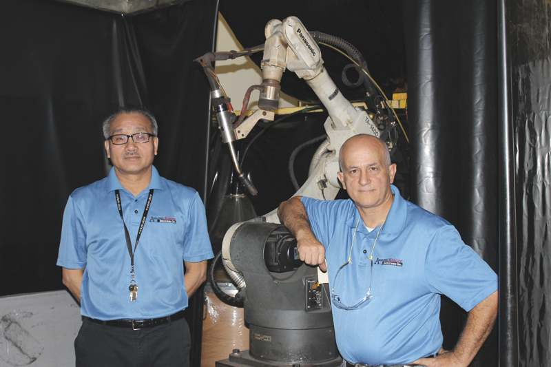 Fred Lai, left, with Amedeo Pellegrino, senior vice president, in front of one of the shop's robotic welding systems.