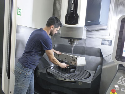 Calin Veres, machine programmer, adjusts the workholding system in a DMG MORI machine.