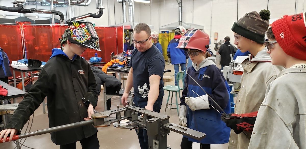 Richard Alexander shows students how to bend a welding rod